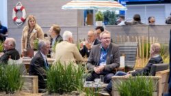 Visitors to the EuroCIS 2022 trade fair sit together in a summer vacation lounge with parasol, life belt and sand; copyright: Messe Düsseldorf/A. Wiese